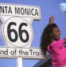 Schild End of Route 66 mit Frau, Santa Monica, Kalifornien - Credit: Santa Monica Travel & Tourism
