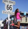 Schild End of Route 66 mit Frau, Santa Monica, Kalifornien - Credit: Santa Monica Travel & Tourism