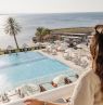 Frau blickt auf Pool und Strand, Crowne Plaza Muscat - Credit: Crowne Plaza Muscat, IHG